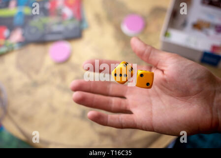 The hand throws two yellow dice on the playing field. Luck and excitement. The concept of Board games. Gaming moments in dynamics Stock Photo