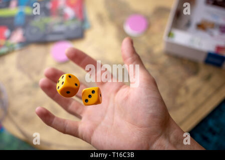The hand throws two yellow dice on the playing field. Luck and excitement. The concept of Board games. Gaming moments in dynamics Stock Photo