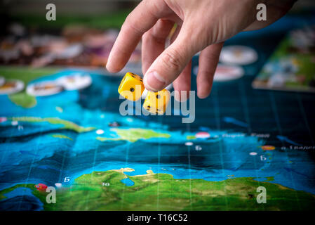 The hand throws two yellow dice on the playing field. Gaming moments in dynamics. Luck and excitement. Board games strategy Stock Photo