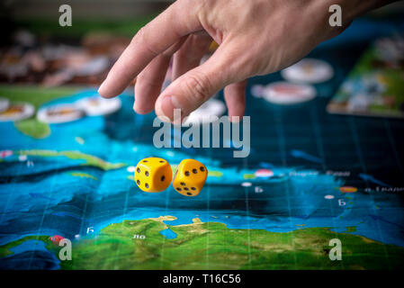 The hand throws two yellow dice on the playing field. Gaming moments in dynamics. Luck and excitement. Board games strategy Stock Photo