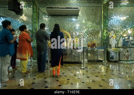 The unique Arulmigu Sri Rajakaliamman Glass Temple in Johor Bahru, Malaysia. The interior is completely covered in glass tiles. Interior and praying. Stock Photo