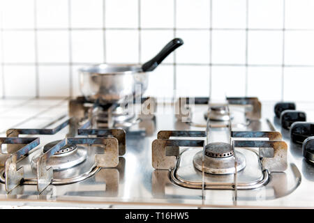 Closeup of vintage retro tiled gas stove top with tiles white countertop and stainless steel pot cooking in kitchen Stock Photo