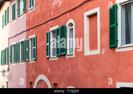 Chiusi, Italy red orange pink bright vibrant colorful walls street in small historic medieval town village in Umbria closeup pattern Stock Photo