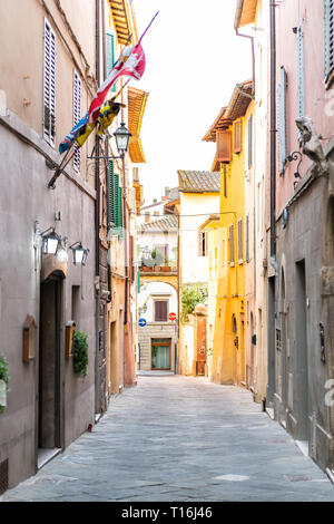 Chiusi, Italy empty street in small town village in Umbria Tuscany narrow vertical view during day with orange pink yellow bright vibrant vivid color  Stock Photo