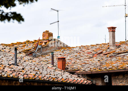 Monticchiello, Italy rooftop with historic old medieval buildings of town village orange colors in summer roof tiles closeup and satellite antennas Stock Photo