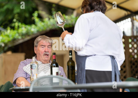 Bagno Vignoni, Italy - August 26, 2018: Medieval town by San Quirico d'Orcia in Val d'Orcia, Tuscany with street restaurant cafe and man people eating Stock Photo