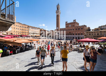 Siena, Italy - August 27, 2018: Street piazza square in historic medieval old town village in Tuscany with crowd of many people tourists travel walkin Stock Photo