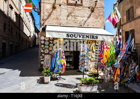 Siena, Italy - August 27, 2018: Historic old town village in Tuscany with shopping souvenirs sign travel street vendor retail display with many object Stock Photo