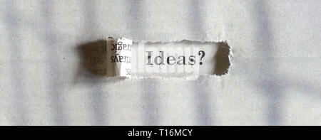 Ideas - word printed on a paper seen through a torn newspaper Stock Photo