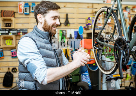 Happy man with passionate emotions standing near a new bicycle at the bicycle shop Stock Photo