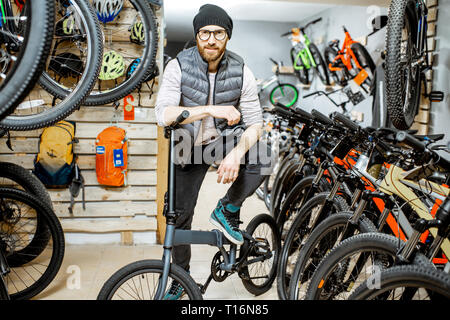 Portrait of a stylish man with folding bicycle at the bicycle shop Stock Photo