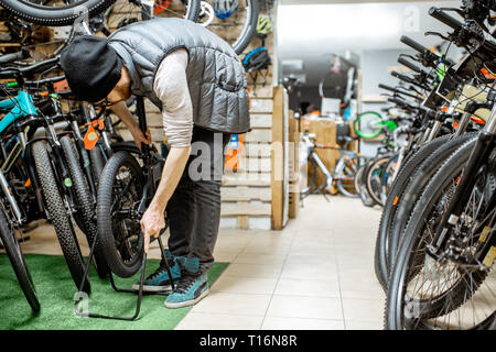 Stylish man making folding bicycle in the bicycle shop Stock Photo