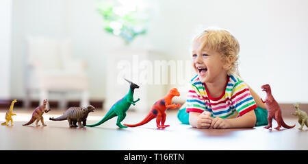 Child playing with colorful toy dinosaurs. Educational toys for kids. Little boy learning fossils and reptiles. Children play with dinosaur toys. Evol Stock Photo
