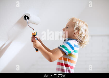 Kids painting attic wall. Home improvement and renovation. Child applying white paint on brick walls in bedroom. Renovating sky parlor with slanted wa Stock Photo