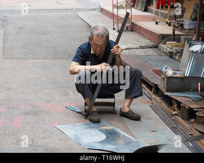 Central, Hong Kong - November 4 2017: An old man crafts an object from metal in the streets of Hong Kong. Stock Photo