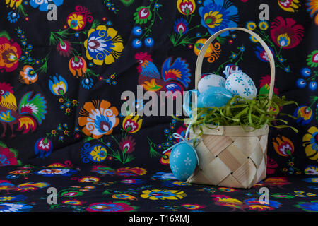 Folk style easter decoration with white and blue eggs and traditional easter cake on painted textile background Stock Photo
