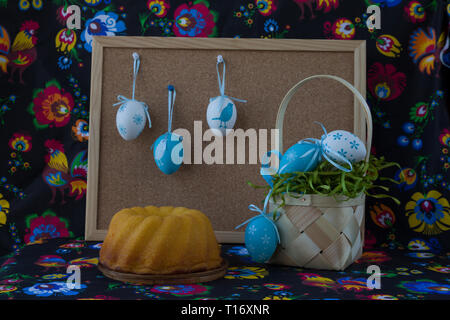 Easter decoration with white and blue eggs on painted textile background with corkboard Stock Photo