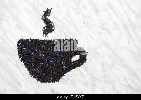 Teacup with steam made of black Earl gray tea leaves, on marble background with copy space. Stock Photo