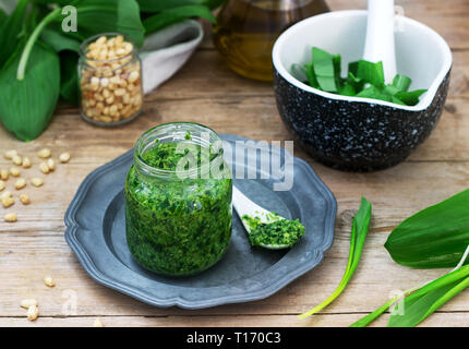 Ramson pesto and ingredients for cooking it on a wooden table. Rustic style. Stock Photo