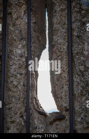 Rusty metal rods and a hole at the weathered and damaged Berlin Wall (Berlin Wall Memorial - Berliner Mauer) in Berlin, Germany. Stock Photo