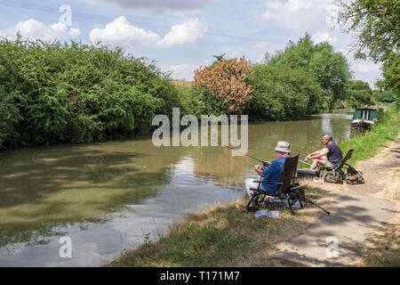 Two male friends, sitting side by side, fishing on the Grand Union canal, Blisworth, Northamptonshire, UK Stock Photo
