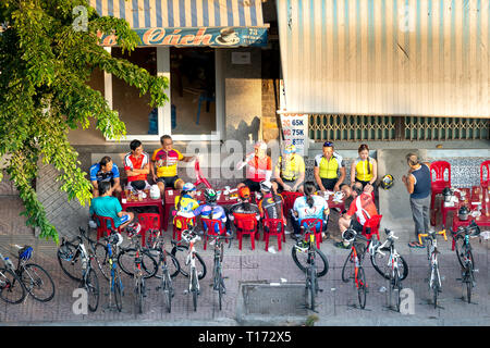 Ho Chi Minh City, Vietnam - February 10, 2019: The older male cyclists taking a break at the small cafe in the street at the morning sunshine Stock Photo