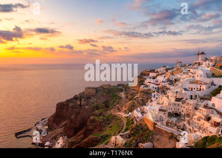 Sunset at traditional white houses in Oia village on Santorini island, Greece.