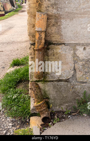 Rusted through, broken down pipe on side of building by Kennet and Avon canal, Bradford on Avon, Wiltshire, UK. Stock Photo