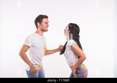 Holiday, social dance, holi and people concept - Happy couple having fun covered in paint and dancing bachata or kizomba on white background Stock Photo
