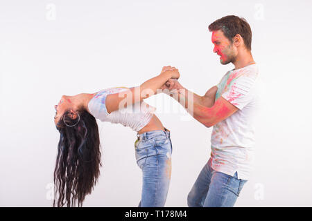 Holiday, social dance, holi and people concept - Happy couple having fun covered in paint and dancing bachata or kizomba on white background Stock Photo