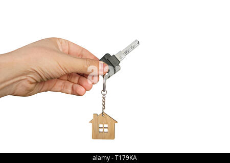 Close up of male hand at white background holding key with wooden house key ring. Concept of purchasing or renting dwelling. Open the door of new apar Stock Photo