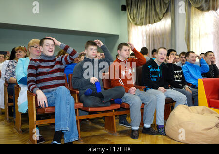 Down syndrome children sitting in chairs during meeting at the conference hall of a boarding school. February 12, 2019. Kiev, Ukraine Stock Photo
