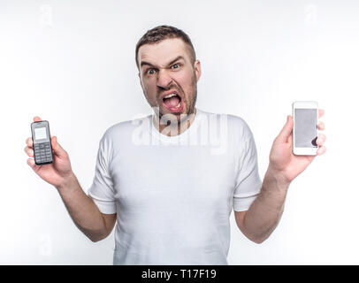 Stressed man is holding two different phones made in different years. Technologies are changing so fast that this changes are stressful to him Stock Photo