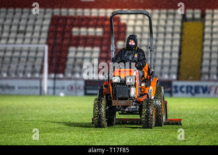 Groundsman maintaining football pitch in rain Stock Photo