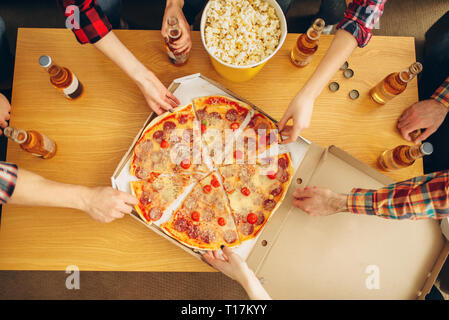 Hands of friends taking slices of pizza from table Stock Photo