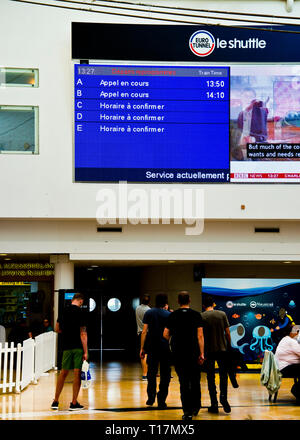 passengers looking up at departure board,standing,sitting,waiting for information about delayed trains at the euro tunnel terminal England,UK. Stock Photo