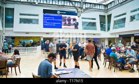 passengers looking up at departure board,standing,sitting,waiting for information about delayed trains at the euro tunnel terminal England,UK. Stock Photo