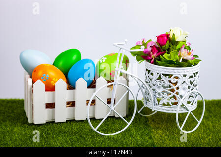 Easter eggs in a white box and decorative bike on green grass. Easter still life. Stock Photo