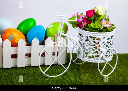 Easter eggs in a white box and decorative bike on green grass. Easter still life. Stock Photo