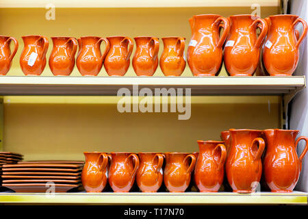 Ceramic crockery jugs and plates are on the store shelf. Stock Photo
