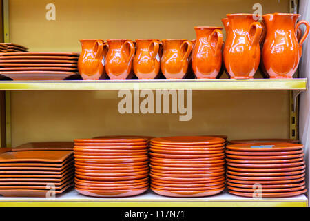 Ceramic crockery jugs and plates are on the store shelf. Stock Photo