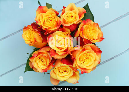Red and yellow rose bouquet covered in glitter shot from the top on wooden surface with copy space Stock Photo