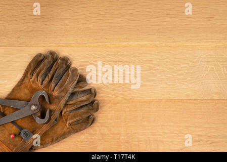 Vintage Pair Of Long Handle Cutting Pliers Nippers and well Worn Leather Work Gloves Wood Background Copy Space Stock Photo