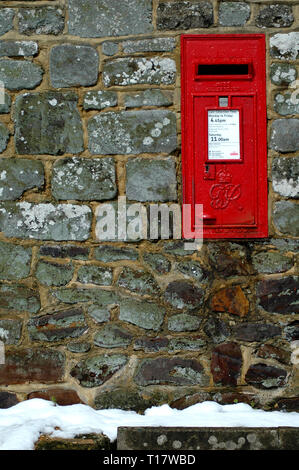 A Royal Mail letter box set into a stone wall with snow on the ground Stock Photo