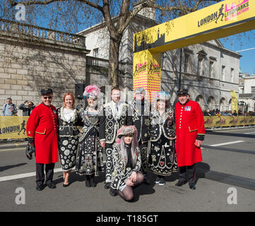 London, UK. 24th March, 2019. The second London Landmarks Half Marathon takes place, starting on Pall Mall and finishing in Whitehall after a route taking in the West End and City of London as far as Tower Hill, with a £6 million charity fundraising target. Charity runners, runners in great costumes, Guinness World Record Attempts and celebrities take part. Image: Pearly Kings and Queens pose with Chelsea Pensioners at the finish gate. Credit: Malcolm Park/Alamy Live News. Stock Photo