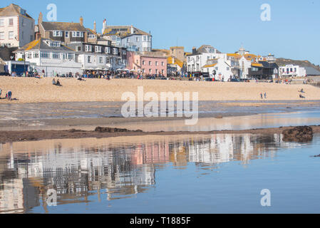 Lyme Regis, Dorset, UK. 24th March 2019. UK Weather: The pretty buildings at the coastal town of Lyme Regis are reflected in the wet sand at low tide on an afternoon of hot sunshine and clear blue skies. Credit: Celia McMahon/Alamy Live News Stock Photo