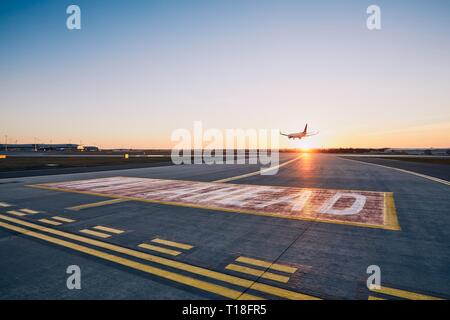 Runway ahead. Airplane landing at airport during sunset. Stock Photo