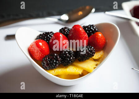 Fruit dish containing pineapple, strawberries and blackberries in a glazed sauce as a breakfast dish. Stock Photo