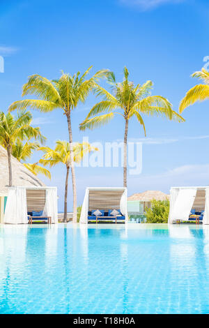 Luxury White beach bed chairs, cabanas, lounge Sundeck by swimming pool side, vertical composition Stock Photo