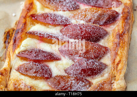 Homemade puff pastry flan with plums, close up. Delicious rectangular galette top view Stock Photo